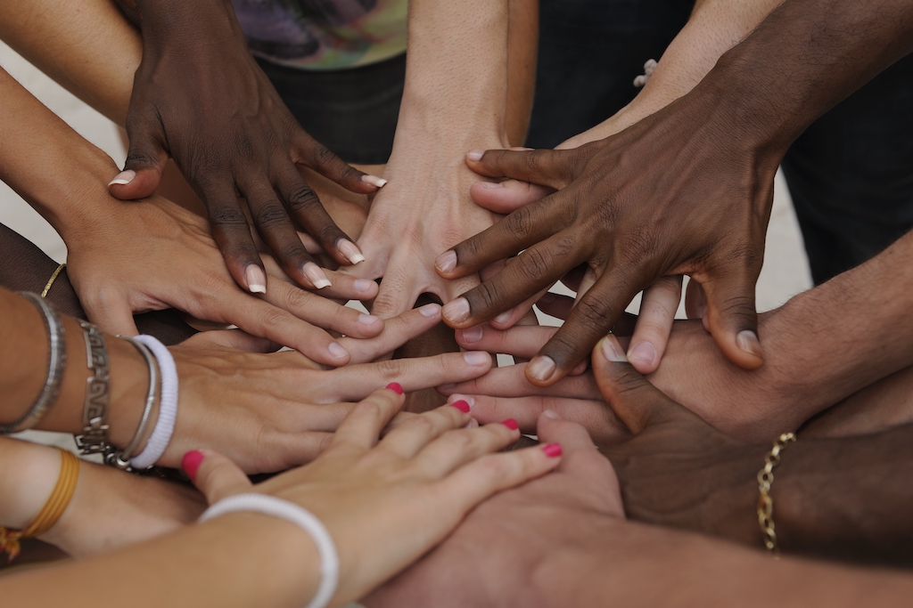 many different races of hands joining in circle