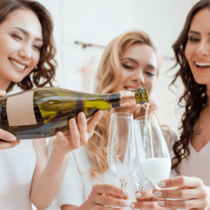3 women in white pouring champagne