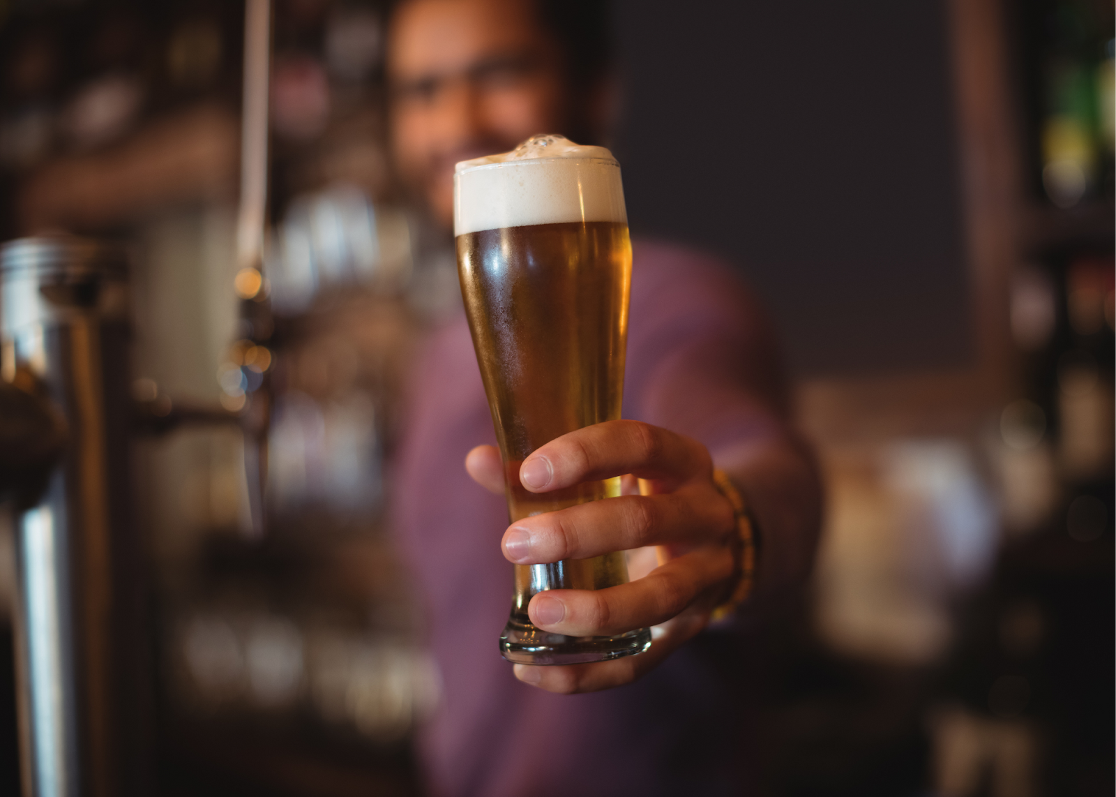 man holding out glass of frothy beer
