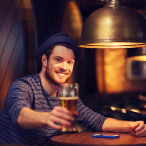 man in blue hat passing a beer