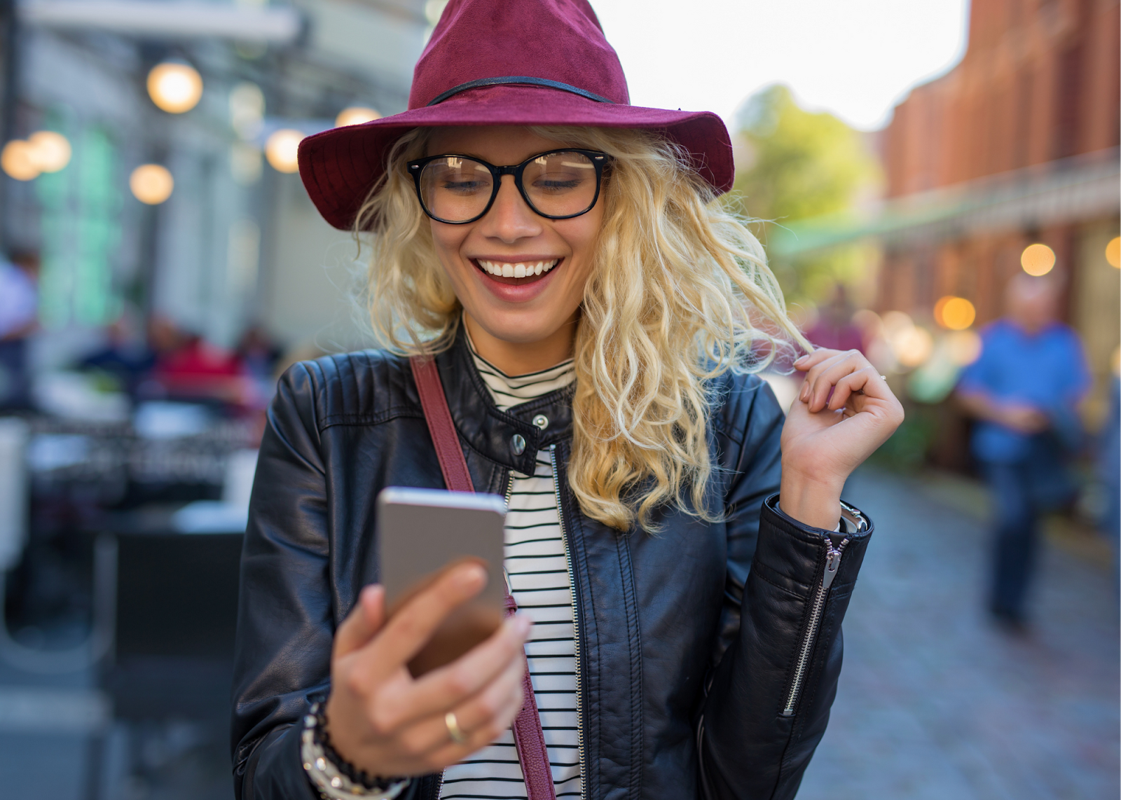 blonde girl with purple hat smiling at phone